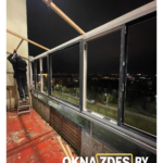 ПВХ-остекление лоджии в темном цвете вечером: поворотно-откидная створка, двухкамерный стеклопакет.