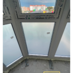 Крупный план створок ПВХ Kömmerling: поворотно-откидные ручки, микропроветривание, энергостекло; внизу тёплые панели.