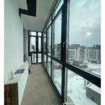 Панорамное остекление длинной лоджии тёмными ПВХ-окнами; много створок, подготовка откосов.