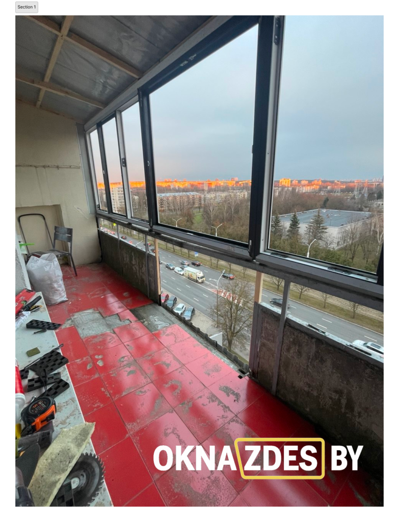 Общий вид лоджии по всей длине с тёплыми ПВХ-окнами антрацит; ночной город за стеклом.