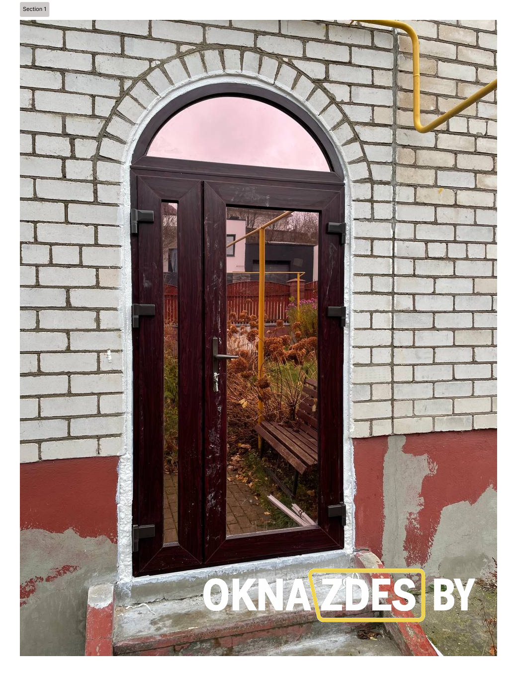 Арочная входная дверь из ПВХ с двустворчатой системой и верхней фрамугой, тёмная ламинация под дерево, остекление.