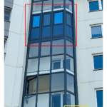 Многоэтажный фасад с витражным эркером; участок тёплого ПВХ-контура выделен красной рамкой (вид с улицы)